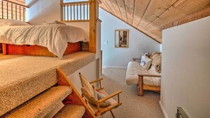 A cozy attic bedroom with a bunk bed, a cushioned chair, and a sofa. - Lincoln Condo w/ Amenities + Shuttle to Loon! (Lincoln)