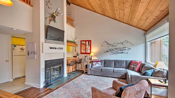 A living room with a fireplace, a sofa, a coffee table, and a rug. - Lincoln Condo w/ Amenities + Shuttle to Loon! (Lincoln)