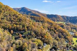 Eine Berglandschaft mit Herbstlaub, verstreuten Häusern und blauem Himmel.