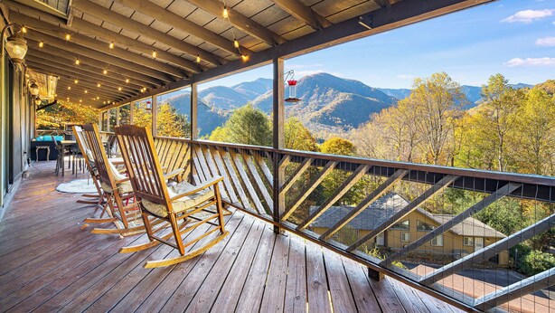A wooden deck with rocking chairs and a view of mountains. - Best Location - Maggie Valley Cabin w/ Hot Tub! (Maggie Valley)