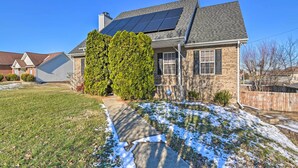 A residential house with a solar panel roof, a brick exterior, and a well-maintained lawn.