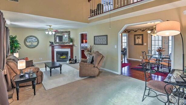 A spacious living room with a fireplace, a dining area with a table and chairs, and a staircase leading to an upper level.