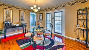 A dining area with a glass table, black metal chairs, and a red and black rug.