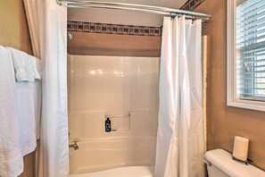 Baño con ducha, inodoro y toallero.