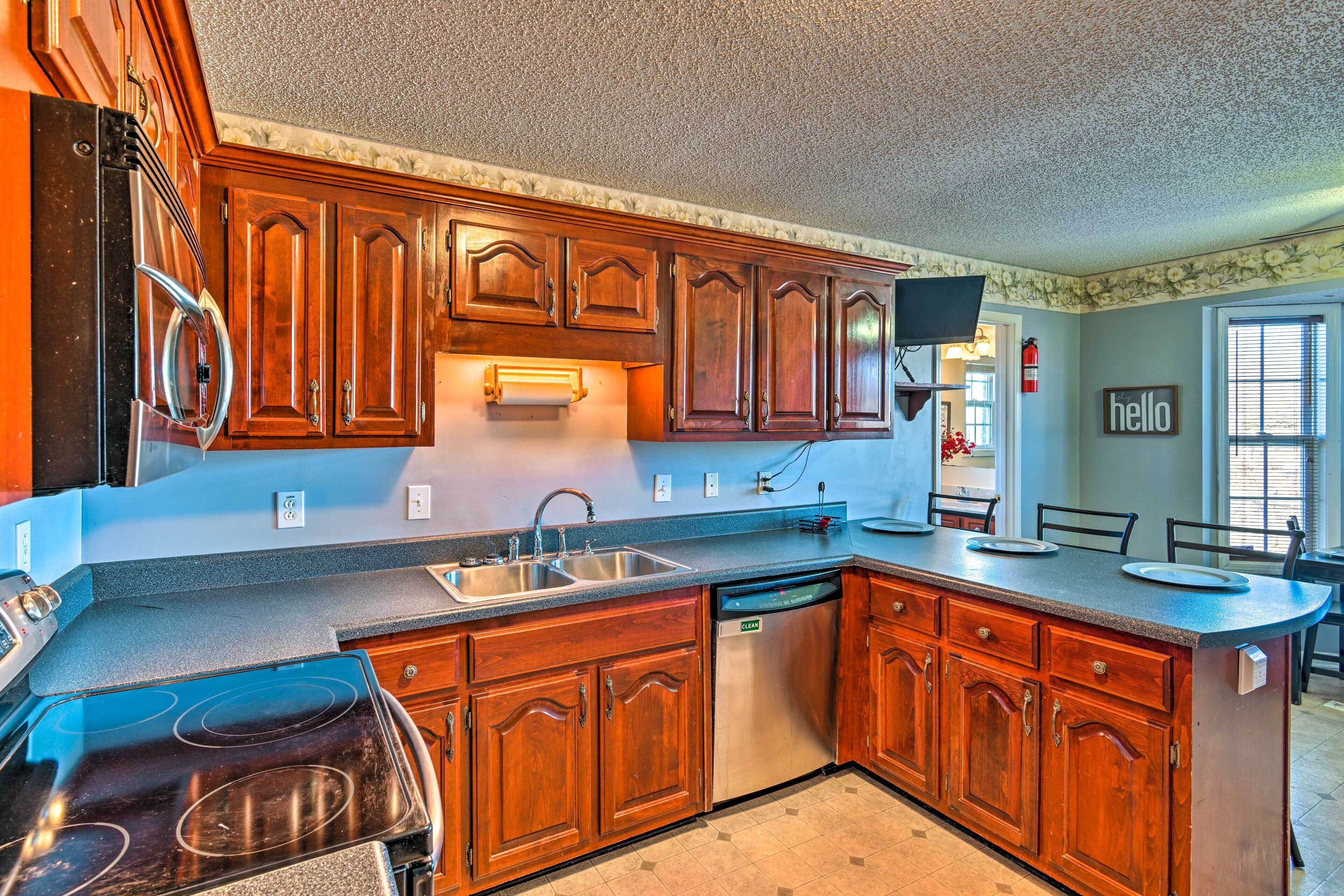 A kitchen with wooden cabinets, a stainless steel refrigerator, a dishwasher, and a large island with a sink.