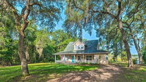 A house with a porch, surrounded by trees and a clear sky.