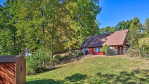 Une maison avec un toit rouge, une terrasse en bois et une cour clôturée.