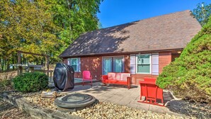 Une maison rouge avec un patio couvert, un foyer extérieur et un banc rouge.
