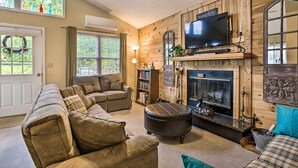 A cozy living room with a fireplace, a television, and a comfortable seating area. - Bring a Pet: Cozy Burnsville Cottage w/ Fire Pit! (Burnsville)