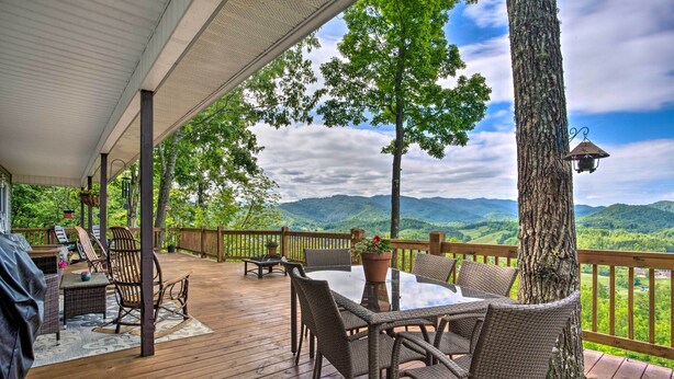 A covered outdoor deck with wicker furniture, a table, and a grill. - Bring a Pet: Cozy Burnsville Cottage w/ Fire Pit! (Burnsville)