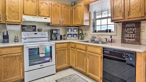 A kitchen with wooden cabinets, a stove, a dishwasher, and a window with a view. - Bring a Pet: Cozy Burnsville Cottage w/ Fire Pit! (Burnsville)