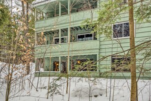 Un edificio de varios pisos con fachada verde, rodeado de árboles y nieve.