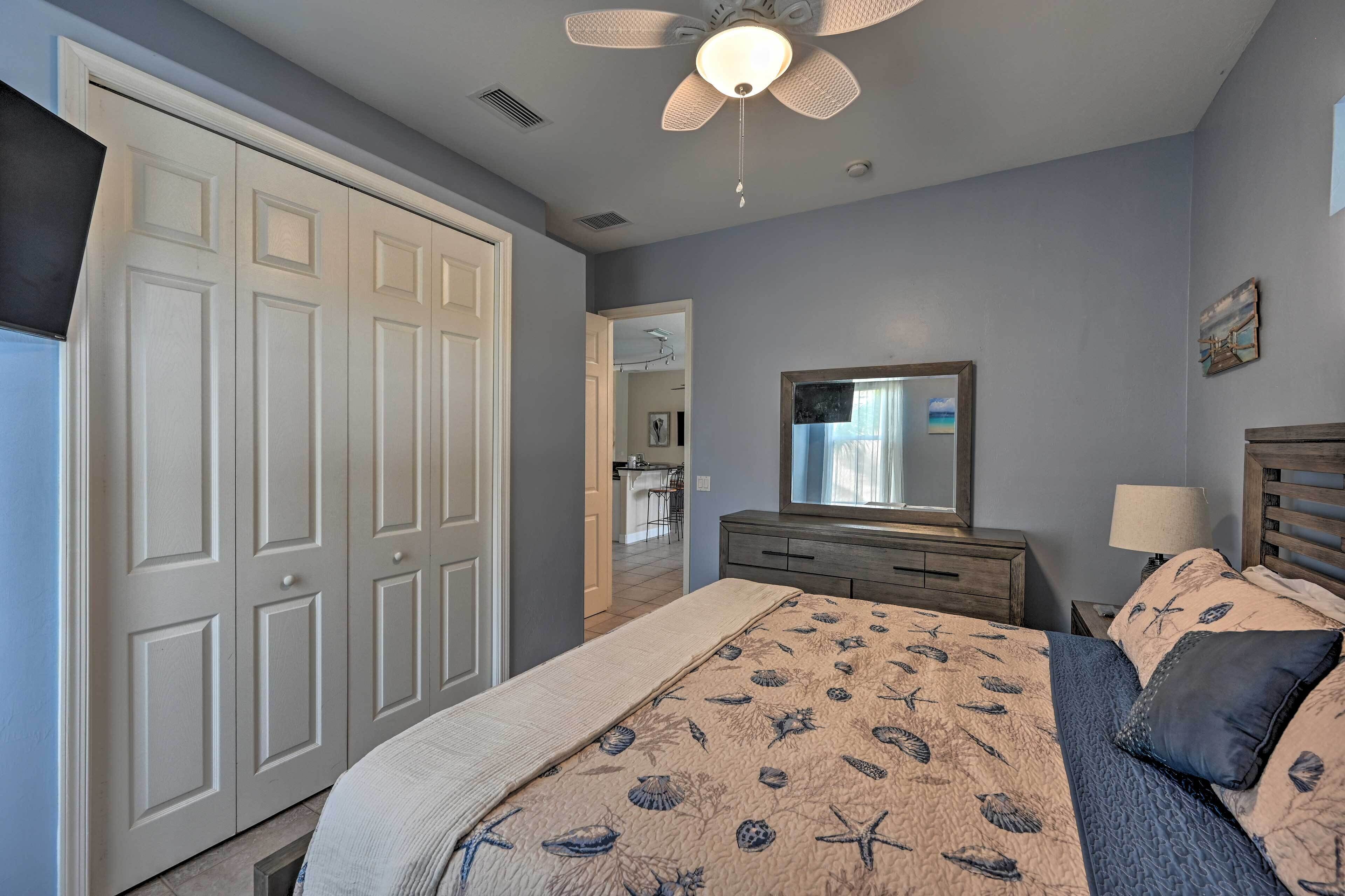 A bedroom with a bed, a dresser, a mirror, and a ceiling fan.