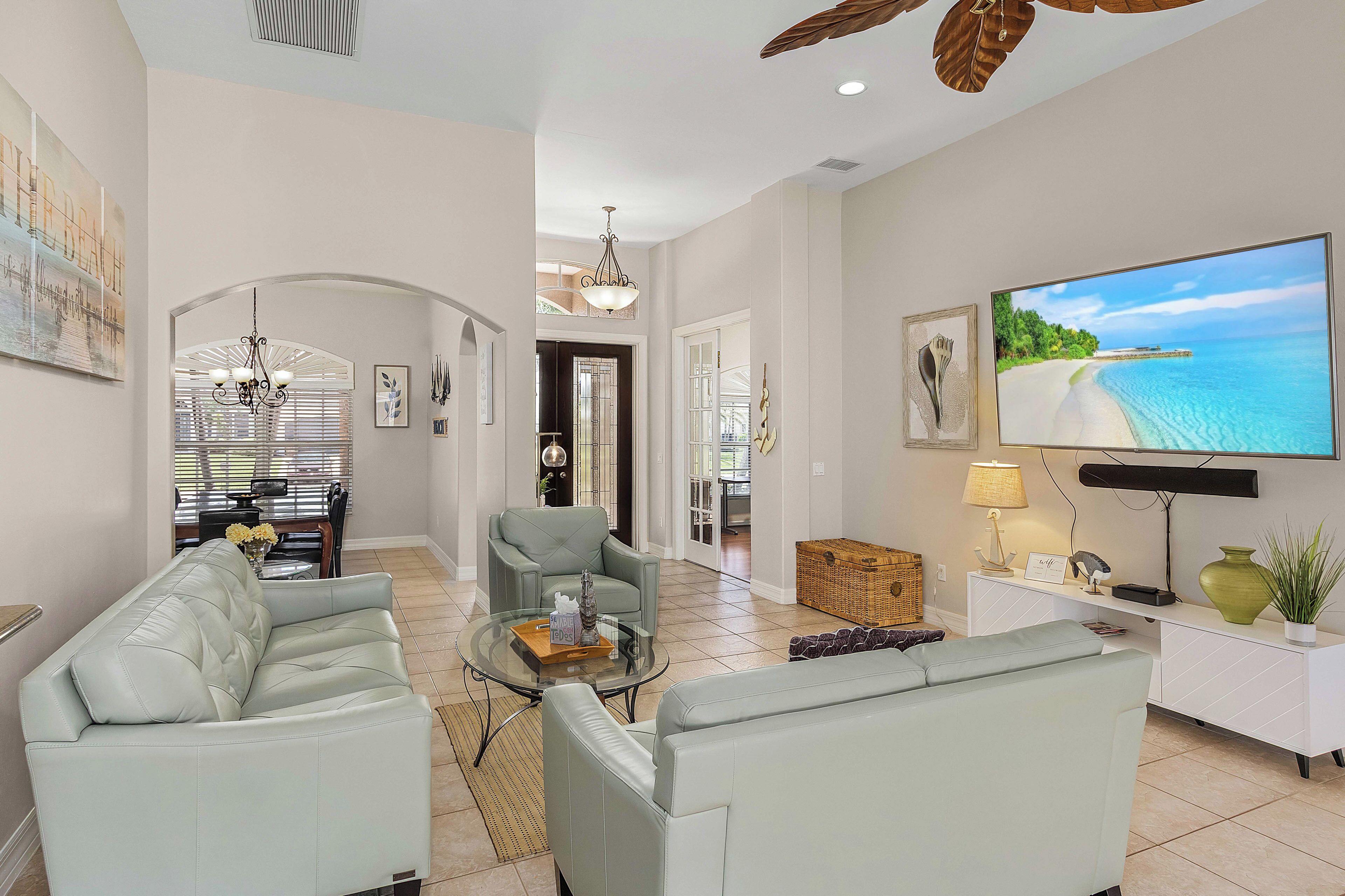 A spacious living room with a large flat-screen TV, comfortable seating, and a dining area with a view.
