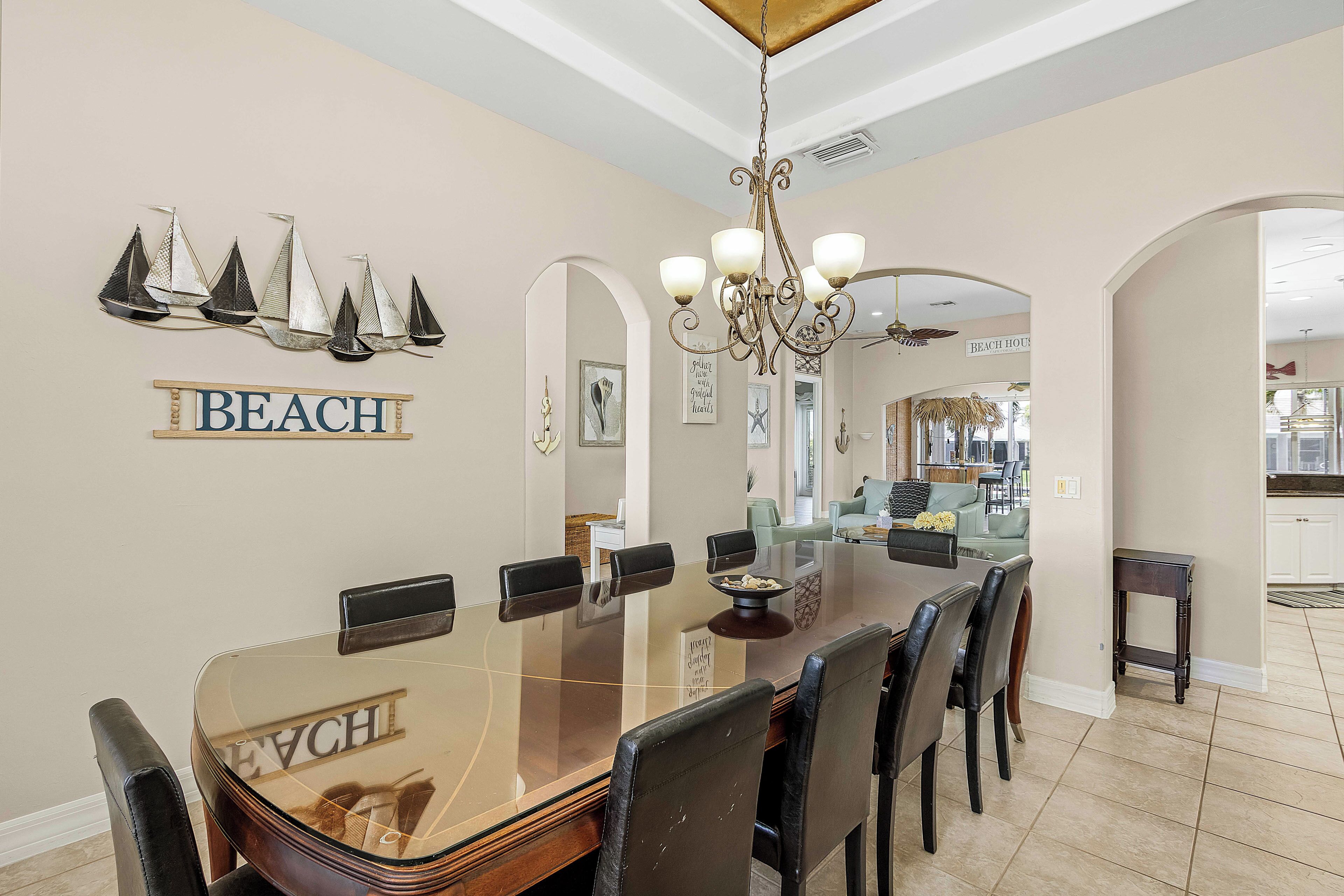 A dining area with a glass-top table, black chairs, and a chandelier.