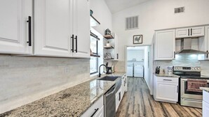 A kitchen with white cabinets, granite countertops, stainless steel appliances, and a wooden floor. - Rural Gilmer House w/ Covered Patio! (Gilmer)