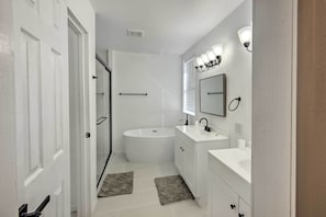 A modern bathroom with a bathtub, vanity, and a mirror. - Rural Gilmer House w/ Covered Patio! (Gilmer)