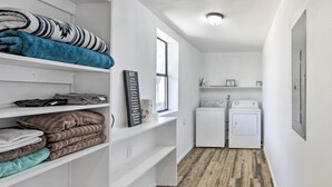 A laundry room with a washing machine and dryer, a window, and shelves with folded towels. - Rural Gilmer House w/ Covered Patio! (Gilmer)