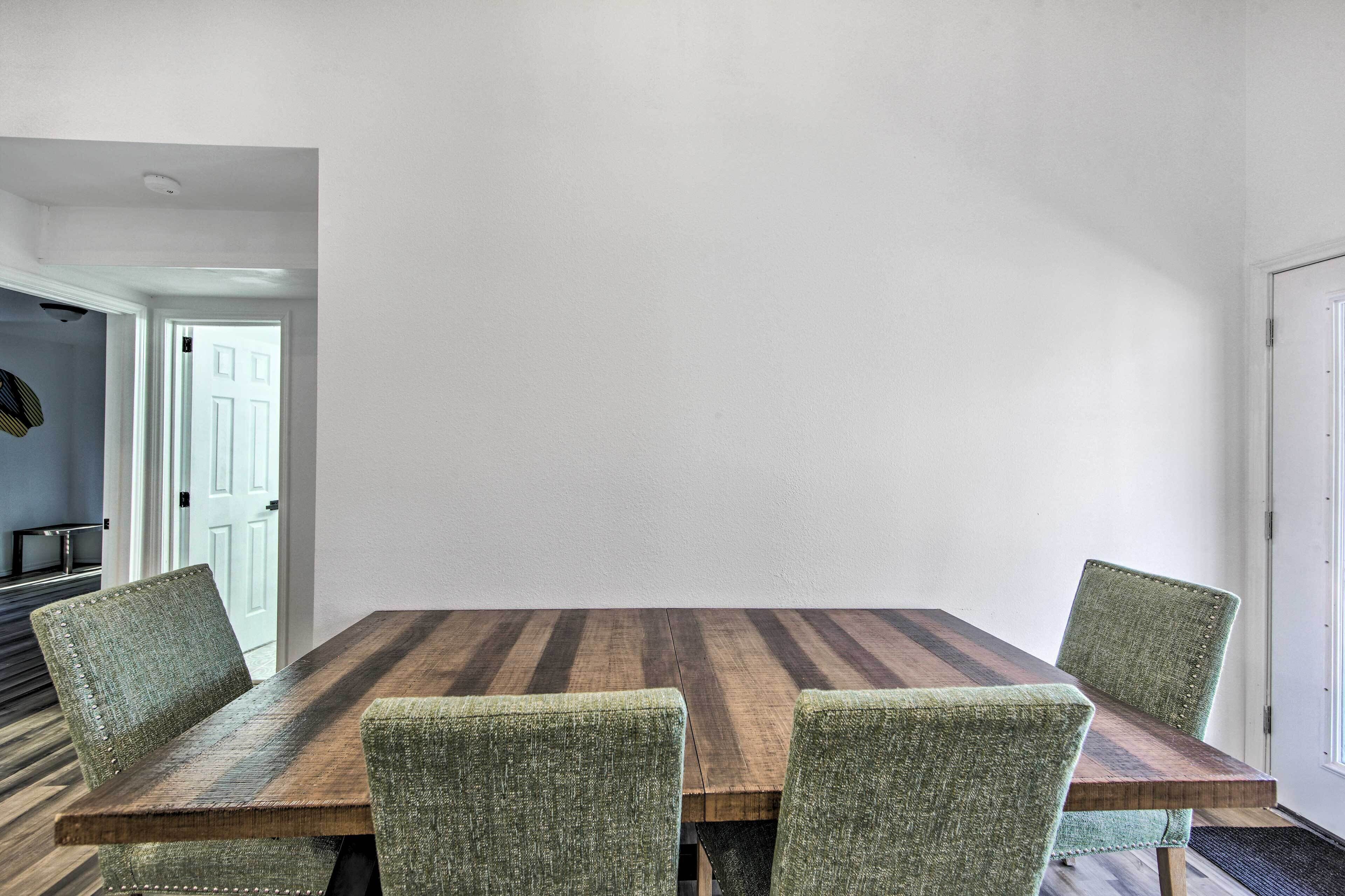 A dining area with a wooden table and four upholstered chairs.