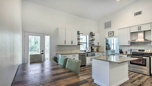 A spacious kitchen with white cabinetry, a central island, and a wooden dining table. - Rural Gilmer House w/ Covered Patio! (Gilmer)