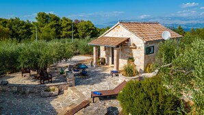 Une maison en pierre avec un toit en tuiles, un espace extérieur aménagé pour s’asseoir et une vue sur le paysage.