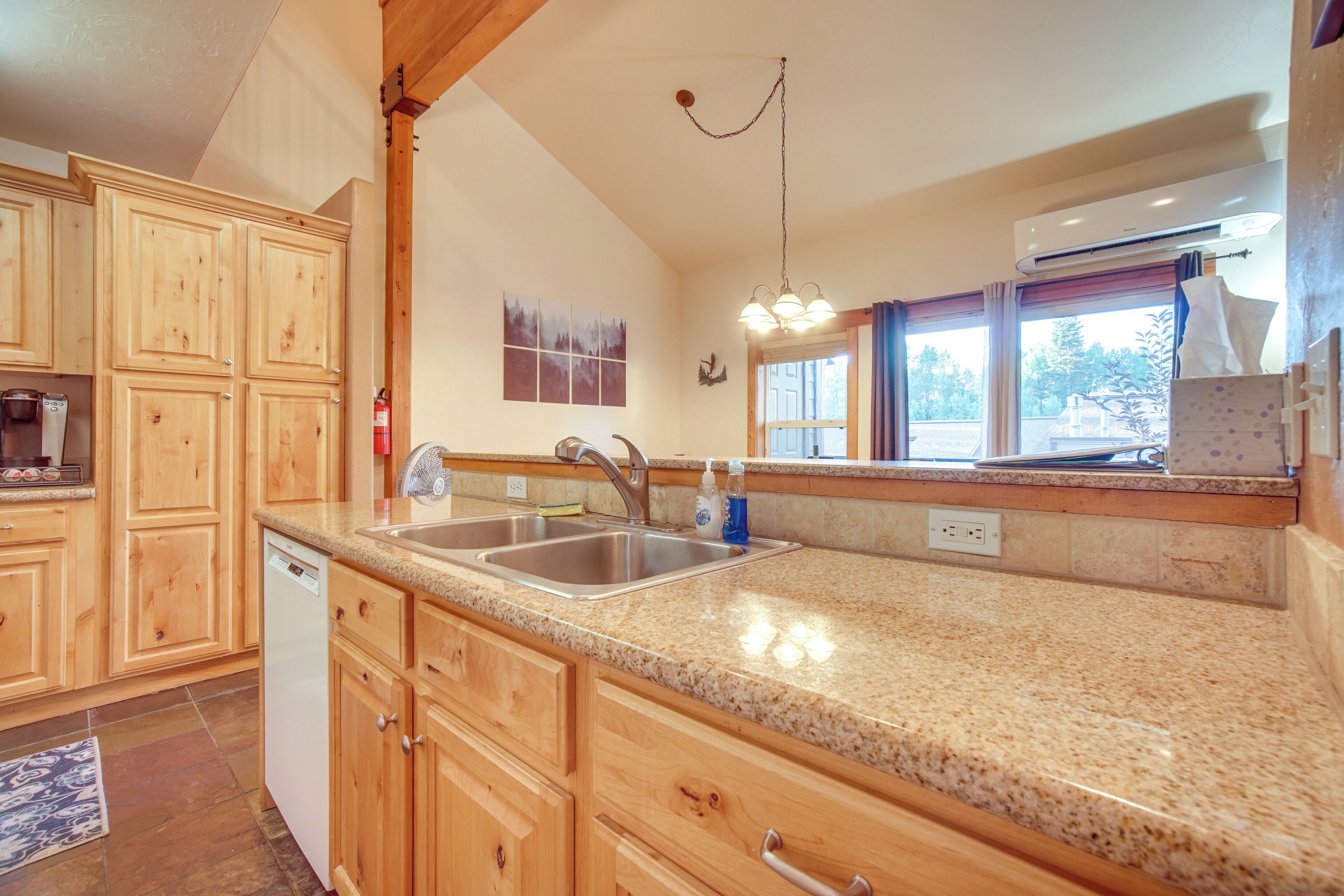 A kitchen with wooden cabinets, granite countertops, a stainless steel sink, and a built-in dishwasher.