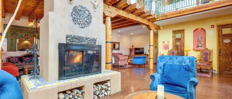 A spacious living area with a fireplace, blue upholstered chairs, and a wooden coffee table.