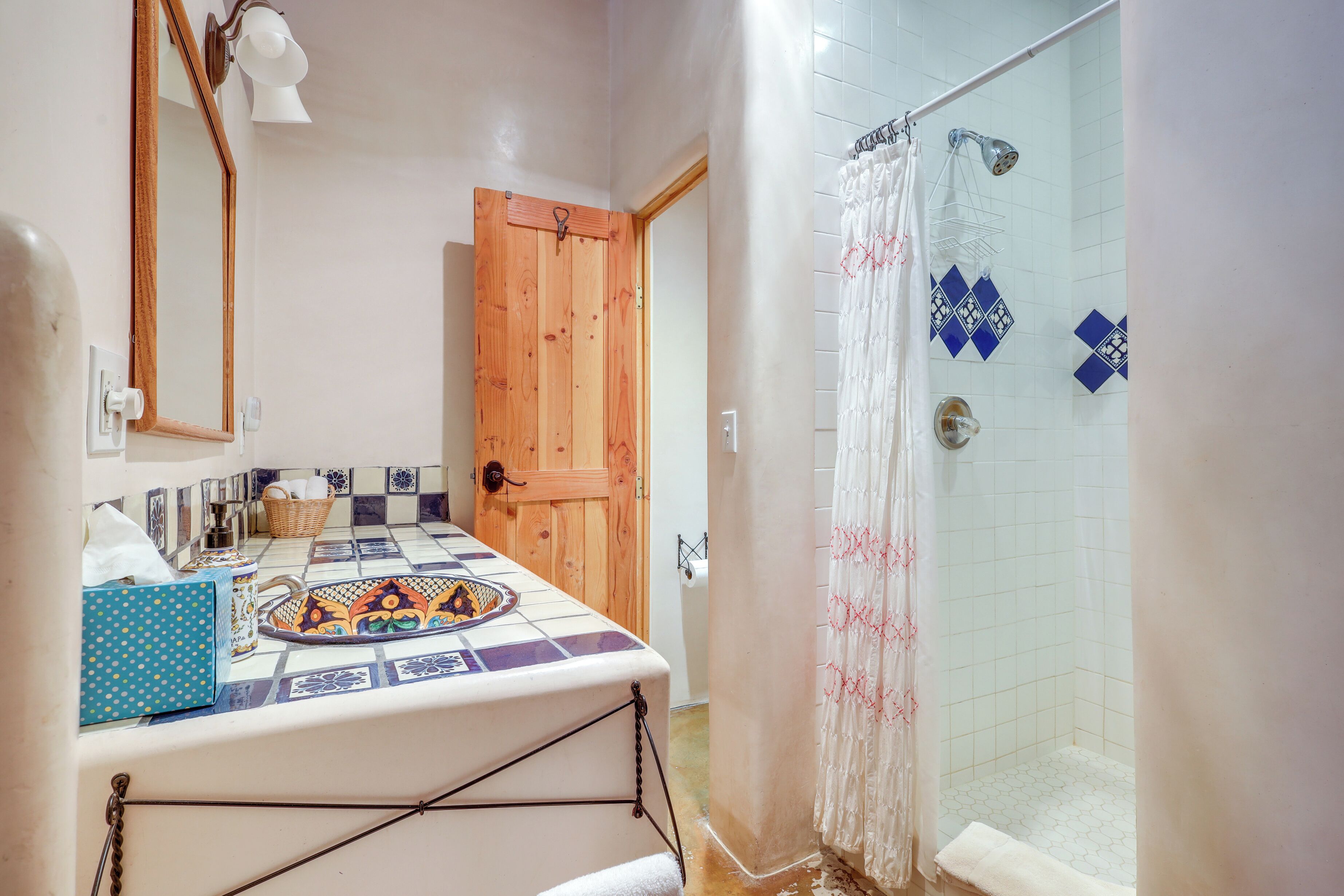 Un baño con puerta de madera, ducha con cortina y salpicadero de azulejos.