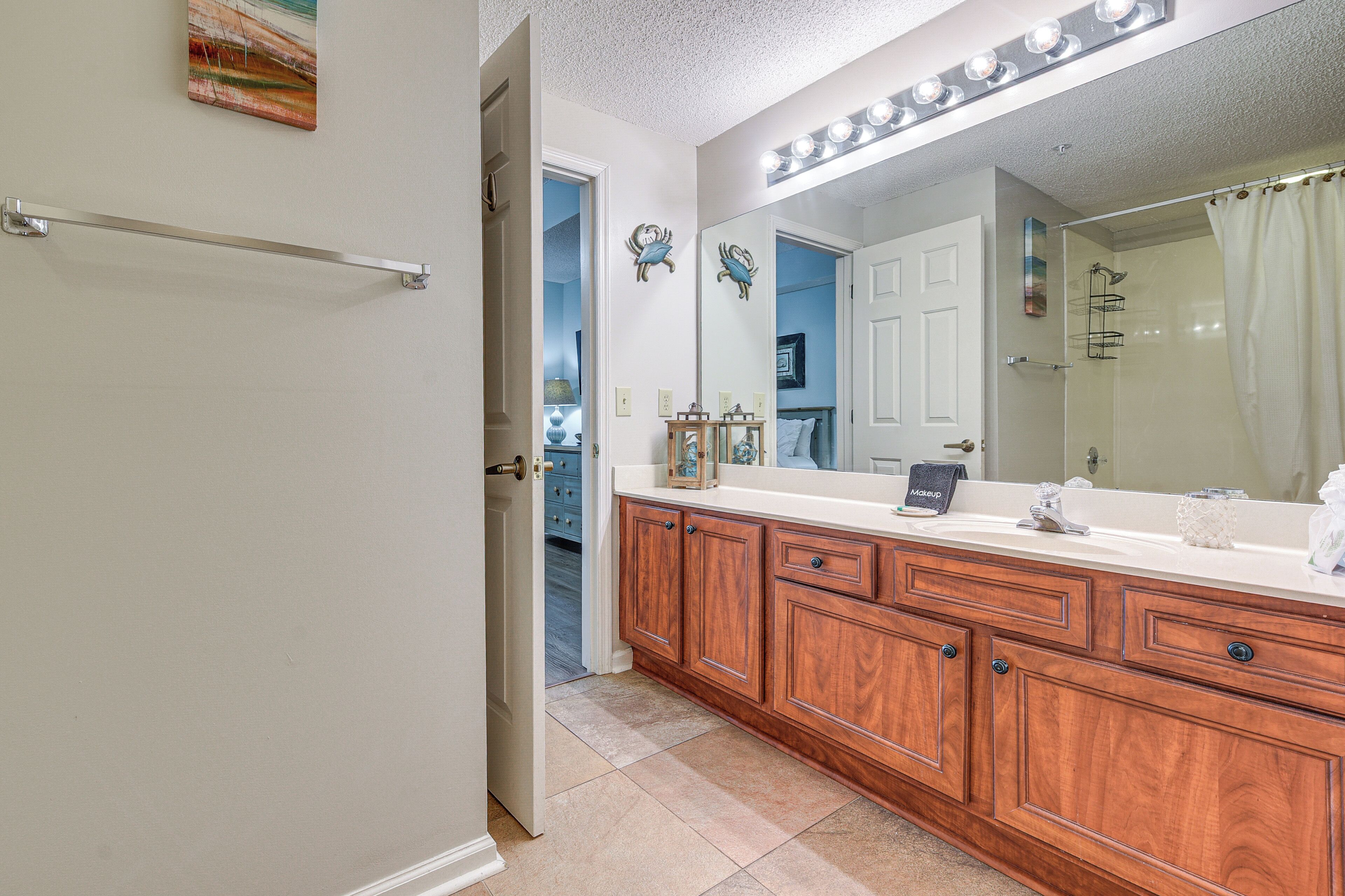 A bathroom with wooden cabinets, a large mirror, and a vanity with a sink.
