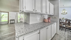 A kitchen with white cabinets, granite countertops, and a chandelier. - Tranquil Creekfront Bryson City Home w/ Grill! (Bryson City)