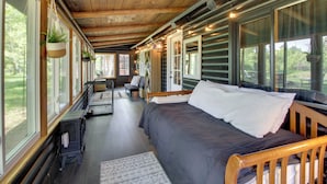 Ein gemütliches Blockhaushaus-Interieur mit einem großen Bett, Holzbalken und großen Fenstern mit Blick ins Freie.