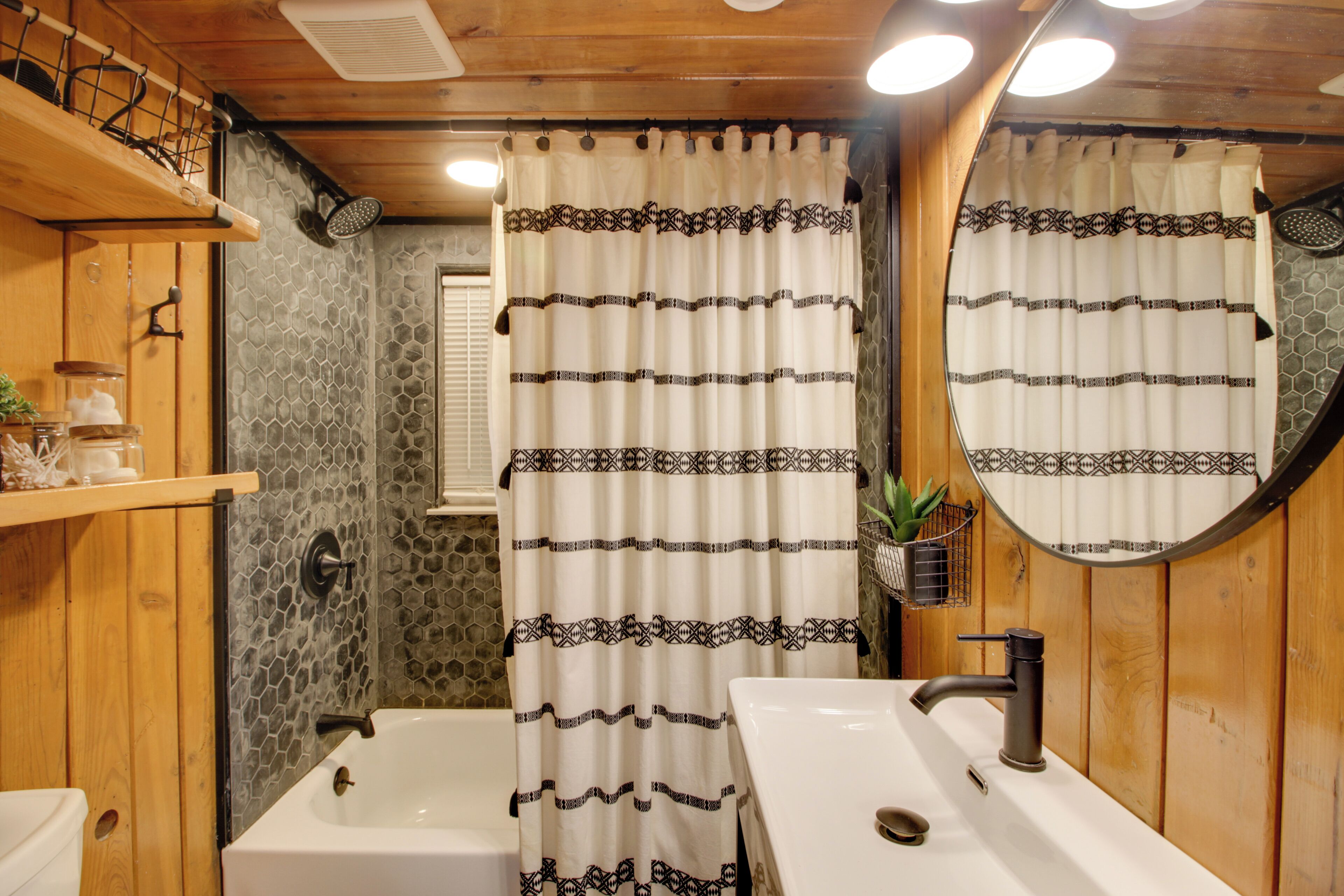 Un bagno con una vasca, un lavandino e una tenda da doccia a motivi geometrici.