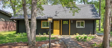 A log cabin with a dark exterior, a front door, and a lantern post.