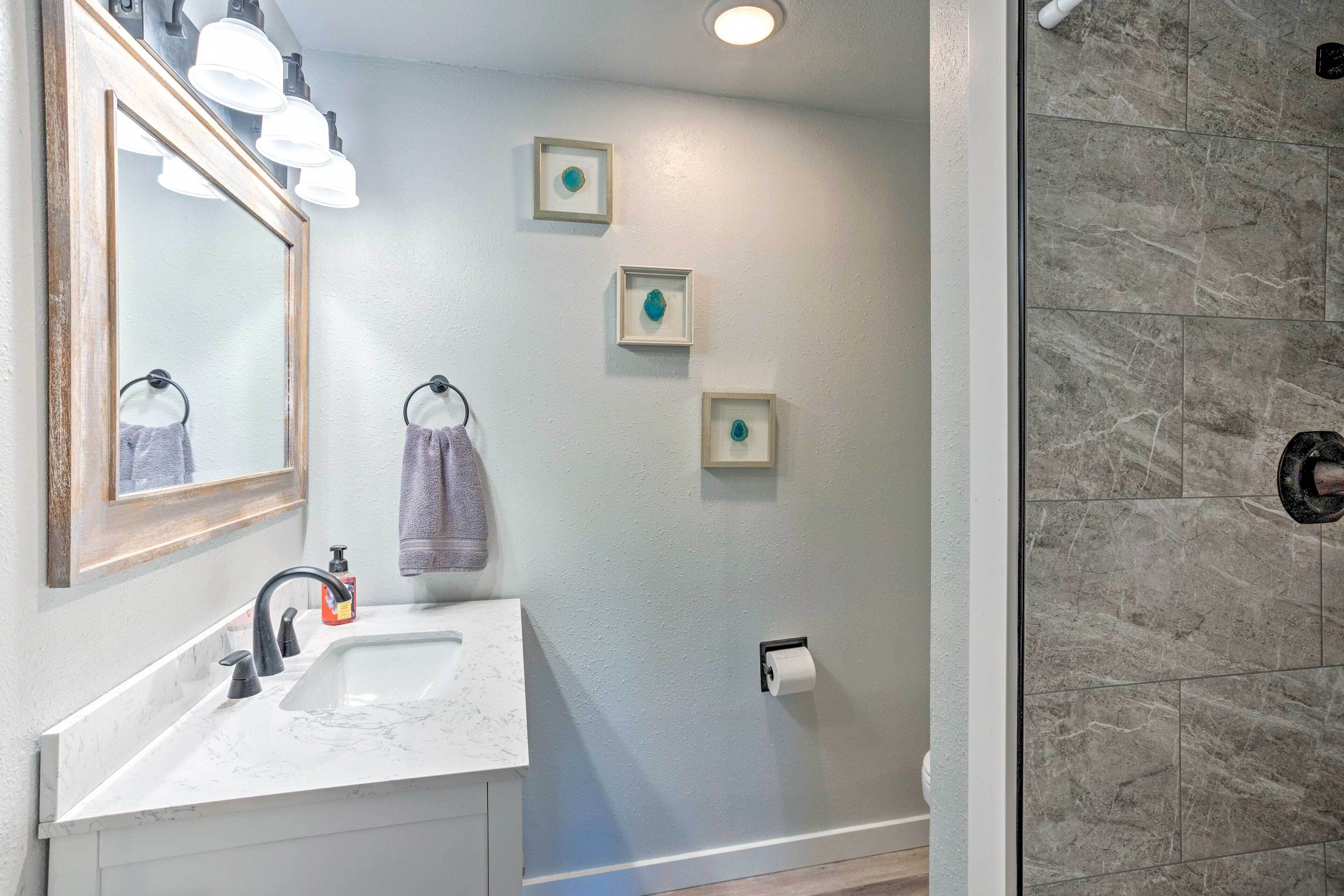 A bathroom with a sink, mirror, towel rack, and framed artwork on the wall.