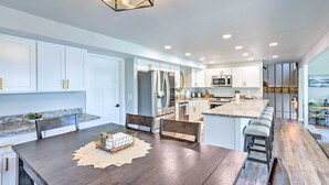 A modern kitchen with white cabinets, stainless steel appliances, and a wooden dining table. - Lakeside Lacey Gem w/ Fire Pit + Private Dock (Lacey)