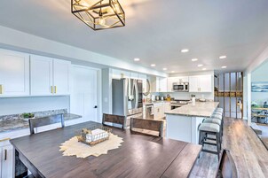 Una cocina moderna con armarios blancos, electrodomésticos de acero inoxidable y una mesa de comedor de madera.