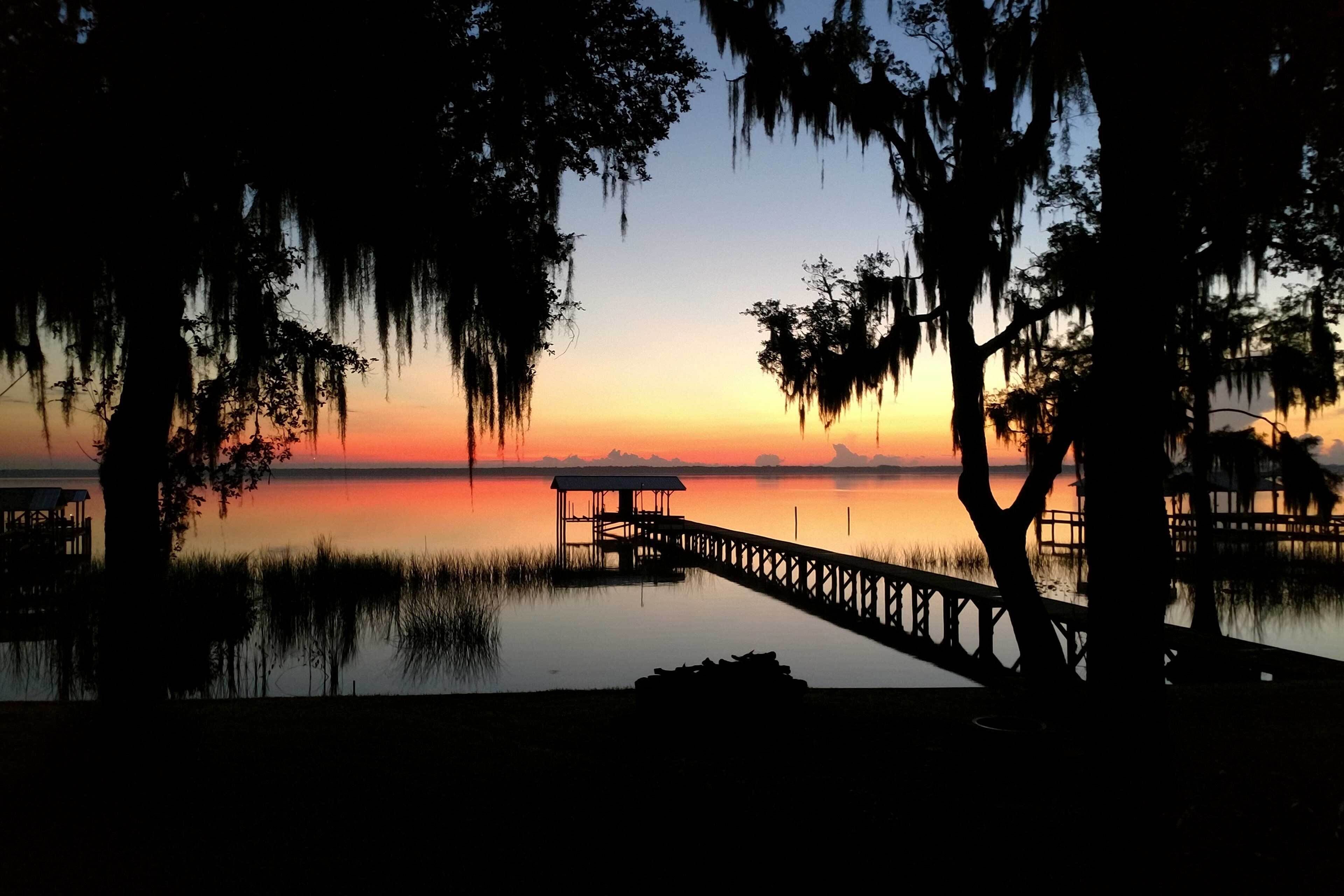 A pier extending into calm water with a sunset in the background.