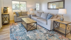 A living room with two sofas, a coffee table, and a TV on a stand. - Renovated Crescent Lake Escape w/ Waterfront Deck! (Crescent City)