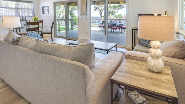 A spacious living room with a sofa, coffee table, and a dining area with chairs and a table. - Renovated Crescent Lake Escape w/ Waterfront Deck! (Crescent City)