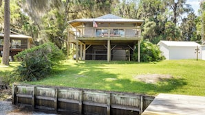 A two-story house with a balcony, a garage, and a flag. - Renovated Crescent Lake Escape w/ Waterfront Deck! (Crescent City)
