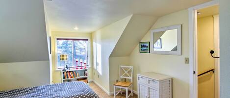 A bedroom with a bed, a chair, a dresser, and a window with blinds.