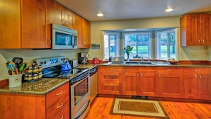 A kitchen with wooden cabinets, stainless steel appliances, and a window with a view of the backyard. - Peacock Hill Retreat on 1 Acre, 1 Mi to Harbor (Gig Harbor)