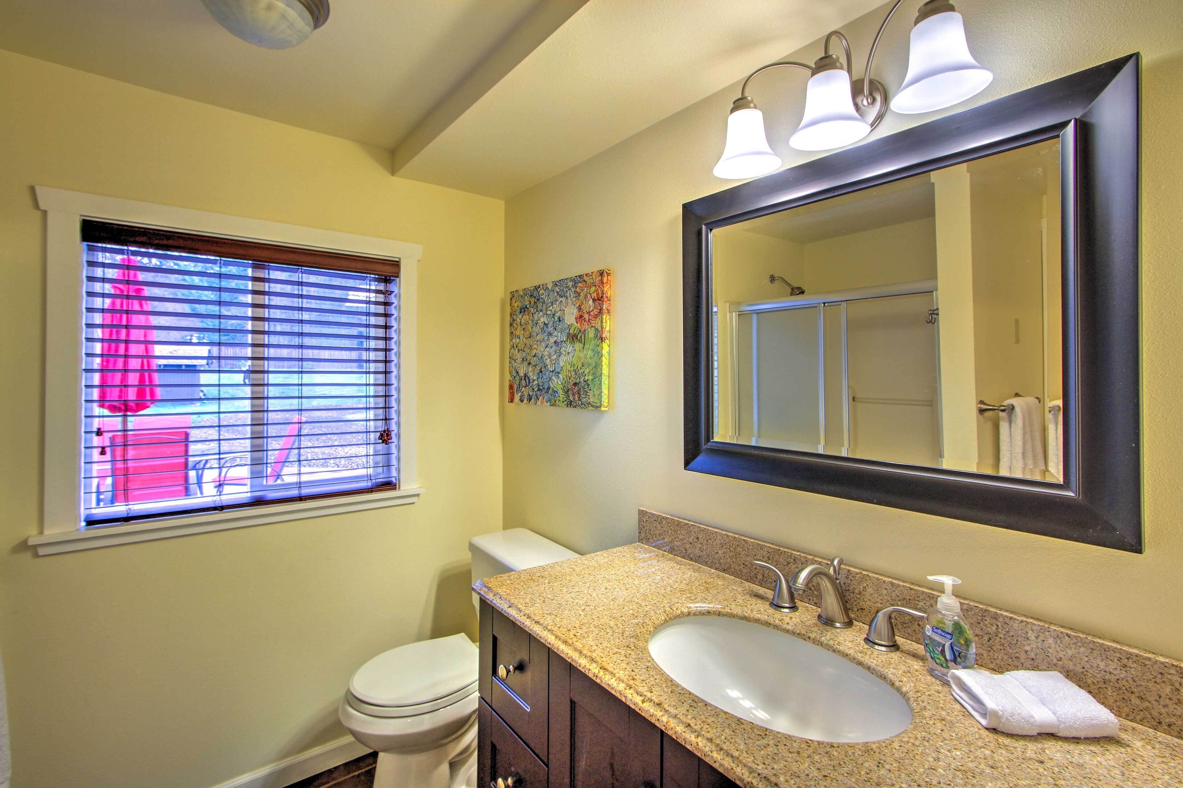 A bathroom with a toilet, sink, and large mirror.