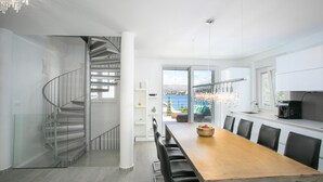 A modern kitchen with a wooden dining table, black chairs, and a view of the sea through large windows. - Stunning Villa Avalon for 9 Pool 2 Mins to Beach (Okrug)