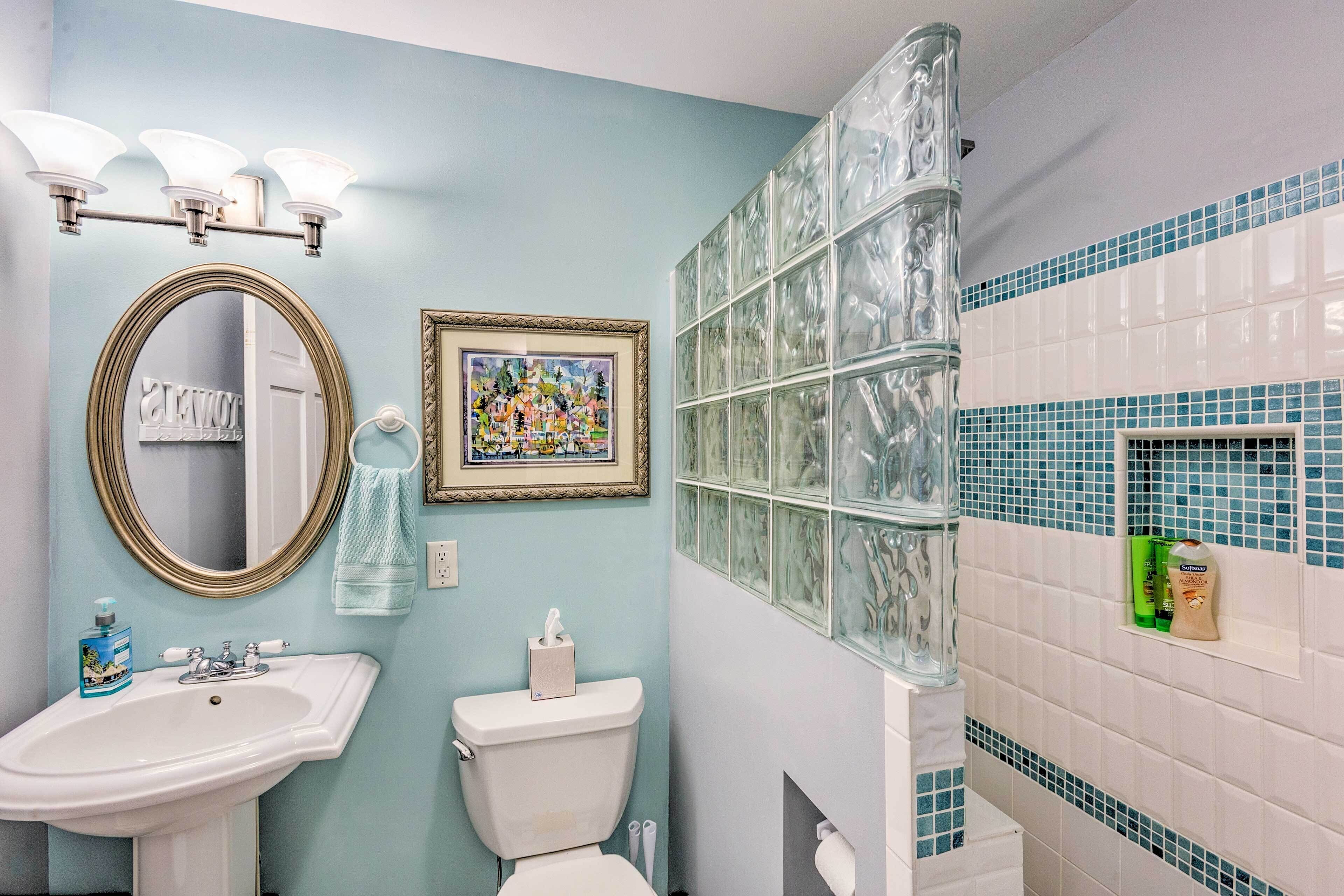A bathroom with a sink, toilet, and a framed picture on the wall.