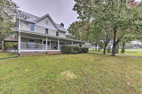 A two-story house with a front porch, a brick foundation, and a lawn. - Remodeled Pittsboro Farmhouse Sitting on 220 Acres (Pittsboro)