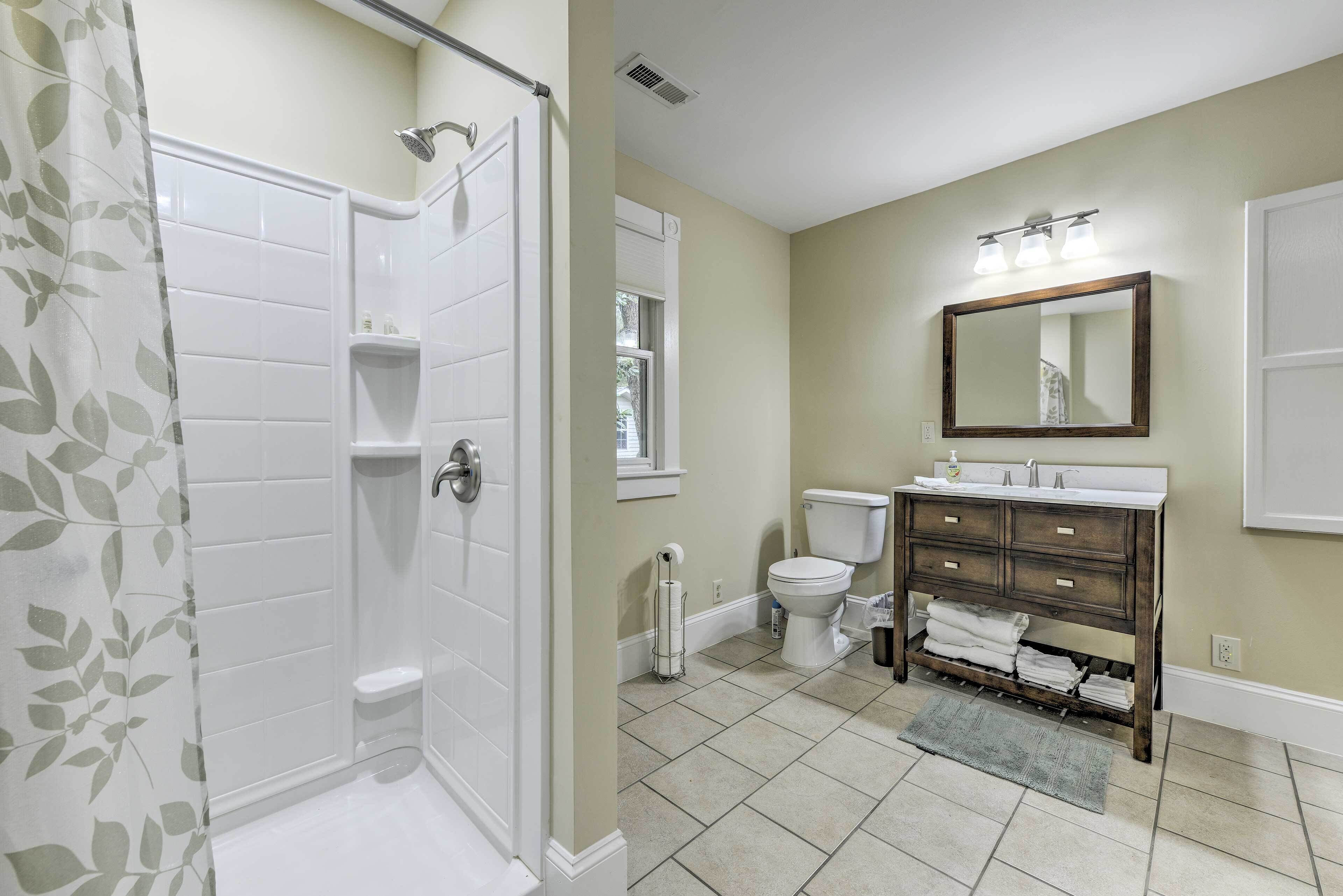 A bathroom with a shower, toilet, sink, and mirror.