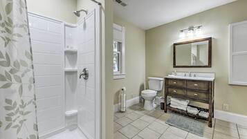 A bathroom with a shower, toilet, sink, and mirror.