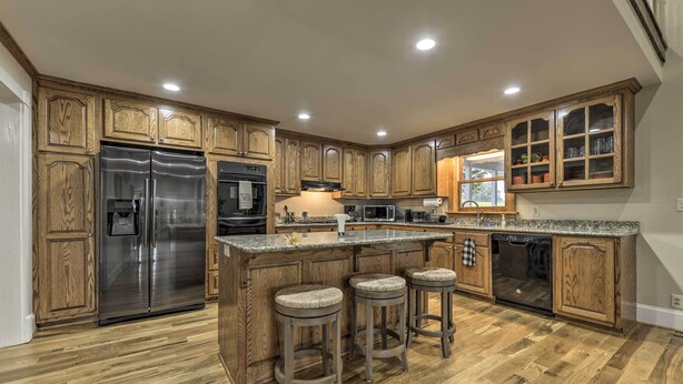 A kitchen with wooden cabinets, a stainless steel refrigerator, a microwave, and a dishwasher. - Remodeled Pittsboro Farmhouse Sitting on 220 Acres (Pittsboro)