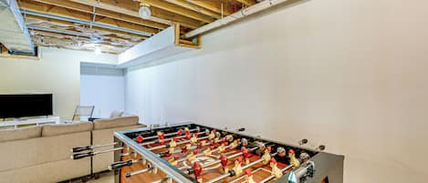 A foosball table in a room with a wooden ceiling and white walls.